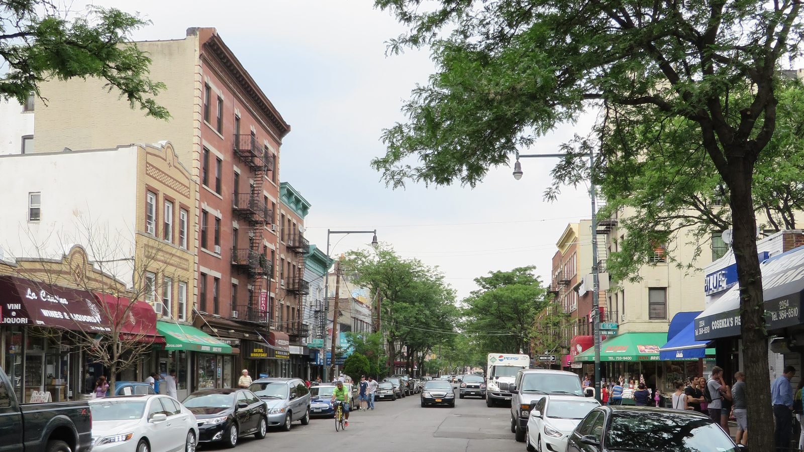 Storefronts, awnings and shoppers along Arthur Avenue in Bronx Little Italy